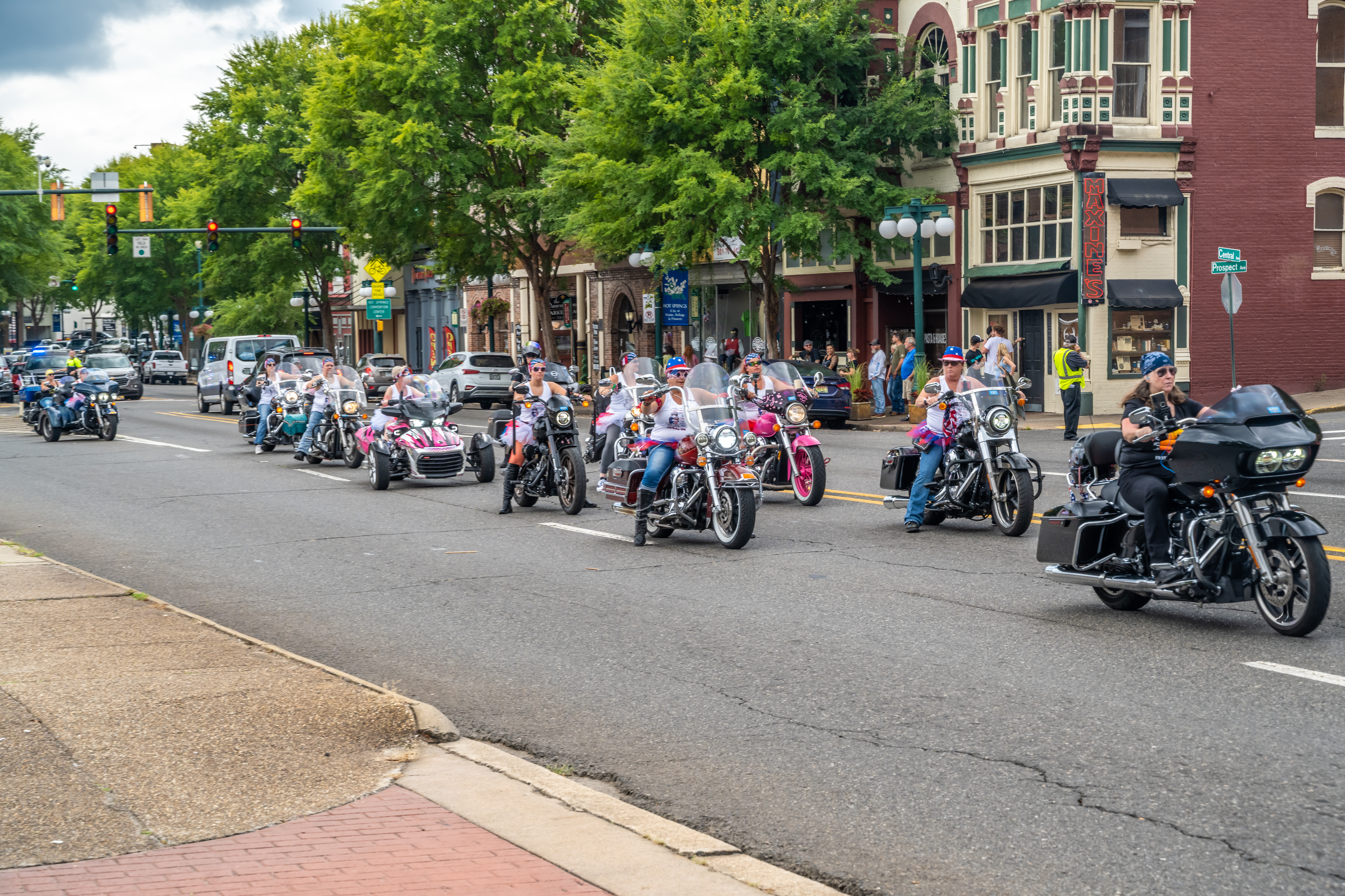 Patriotic Women's Motorcycle Group A large group of women on motorcycles and trikes wearing patriotic hats and shirts, riding past historic brick buildings including "Maxine's" in Hot Springs.