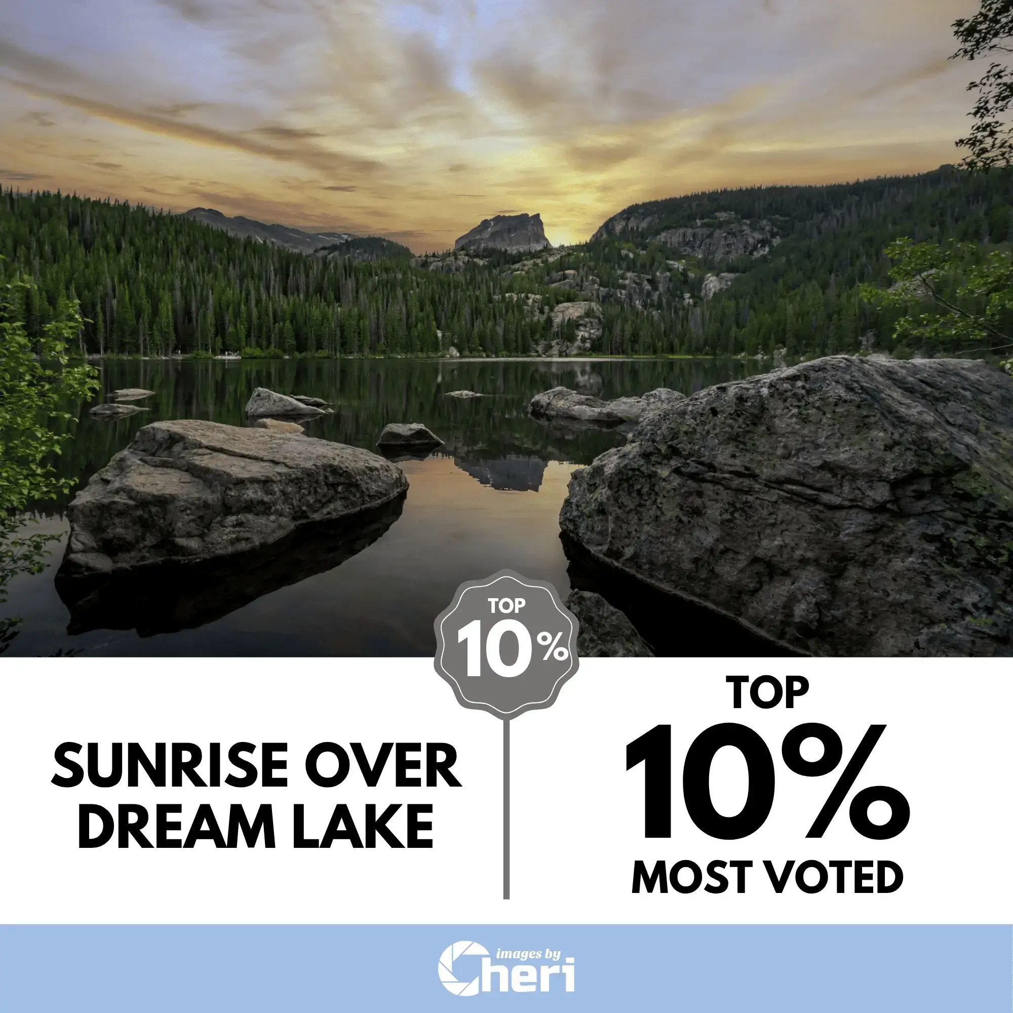 Wide landscape photograph of a colorful sunrise over Dream Lake in Rocky Mountain National Park, featuring two large boulders in the foreground and a mountain peak in the distance. The image was voted Top 10%.