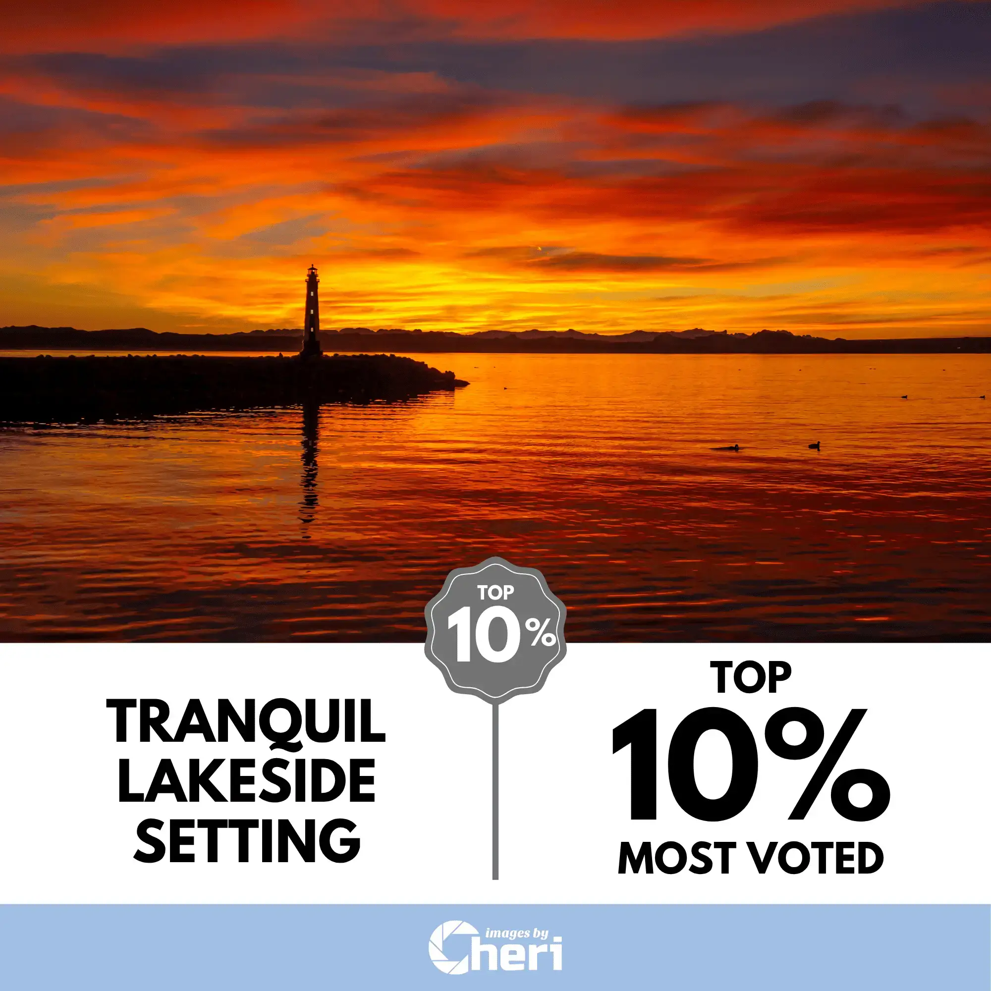 Wide photo titled 'Tranquil Lakeside Setting,' showing a lighthouse on a rocky breakwater reflecting a dramatic, fiery red and orange sunset over a lake. Voted Top 10% in a contest.