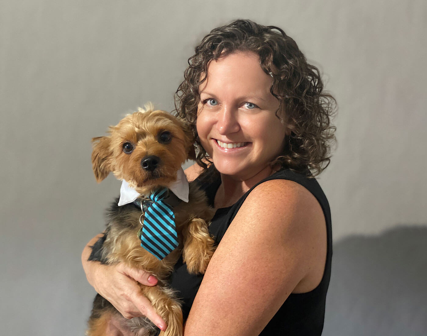 Pet photographer Cheri smiling and holding a small dog during a session