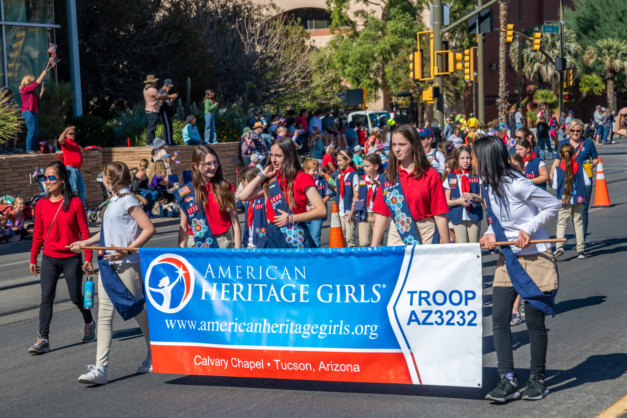 American Heritage Girls Troop Parade Members of American Heritage Girls Troop from Calvary Chapel Tucson walking in a parade holding a large blue and white banner.
