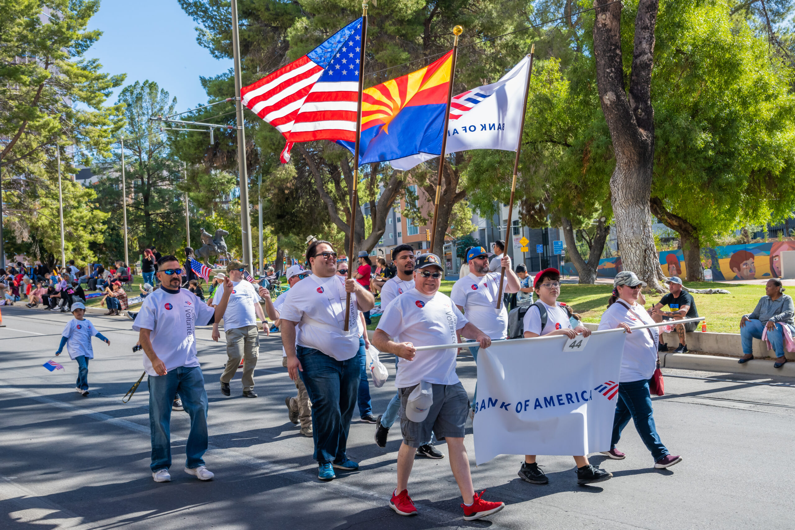 Bank of America Employee Volunteers in Tucson Parade A large group of Bank of America volunteers wearing red t-shirts and carrying blue corporate flags while marching in a downtown Tucson parade.